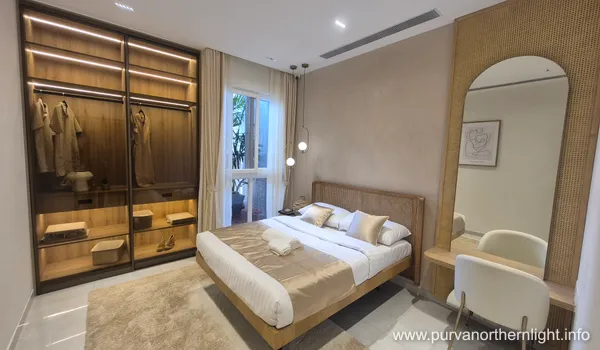 Master bedroom at Purva Northern Lights featuring an open-style illuminated wardrobe and elegant wooden headboard.